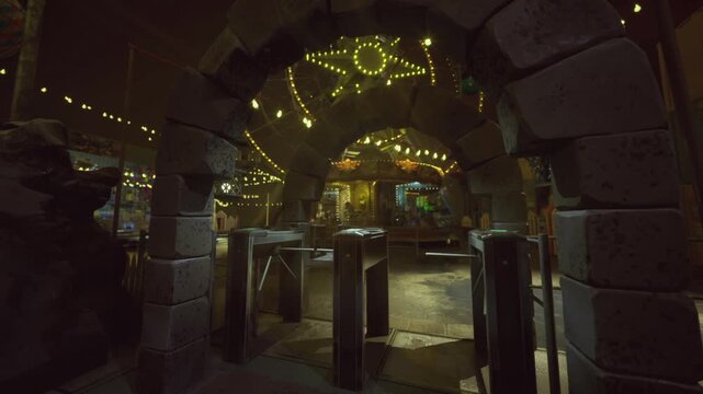 Dimly lit stone arch with star decoration welcomes visitors. Mysterious and shadowed carnival entrance with glowing stars and wet cobblestone path