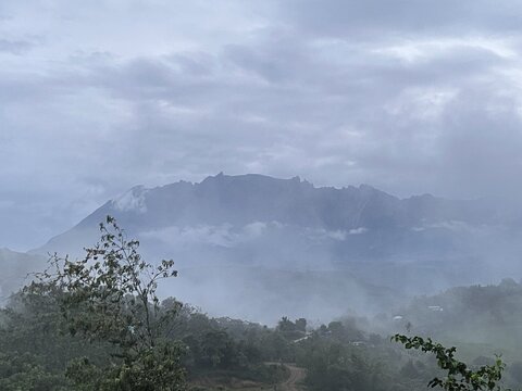 Fog drifting across mountain ridges under a cloudy sky, creating a peaceful and atmospheric natural landscape.