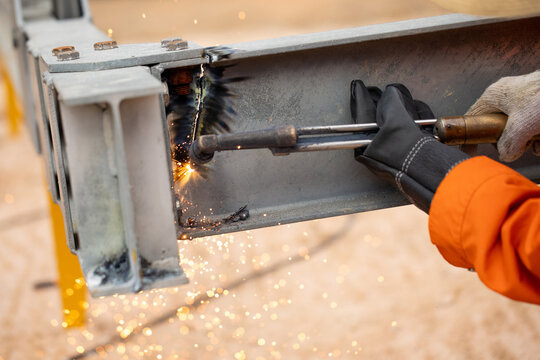 Worker wearing protective gloves while cutting metal with torch demonstrating proper safety