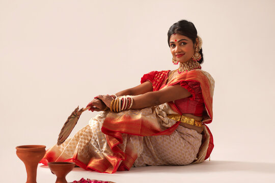 Portrait of Bengali married woman in traditional outfit sitting against white background