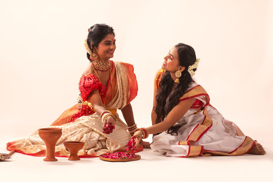 Portrait of mother and daughter in traditional outfit sitting against white background