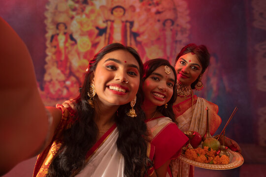 Bengali woman capturing photographs of her mother and sister in Durga Puja pandal