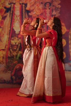 Two Bengali sister playing conch on the occasion of Durga Puja