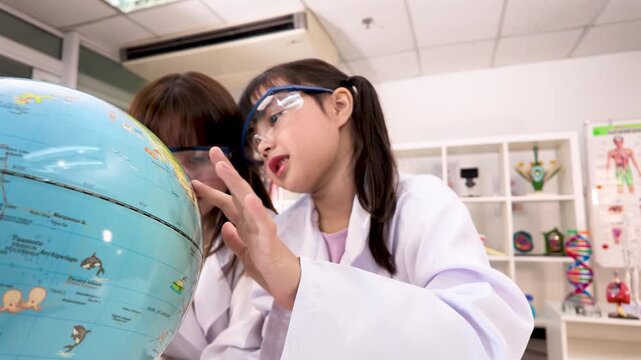 Elementary Students in Lab Coats Studying World Globe in Science Classroom