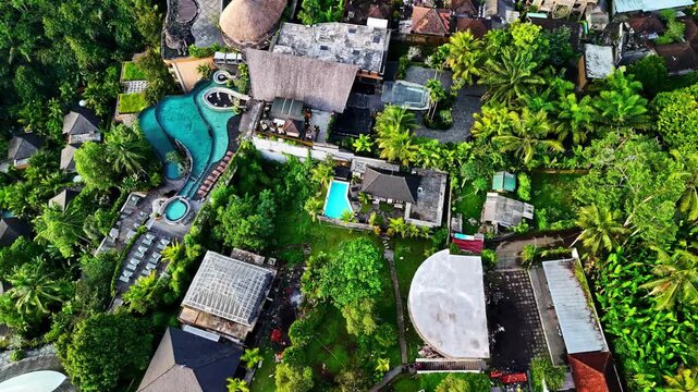 Aerial view of resort complex with swimming pools, lush tropical gardens, and palm trees in Bali, Indonesia.