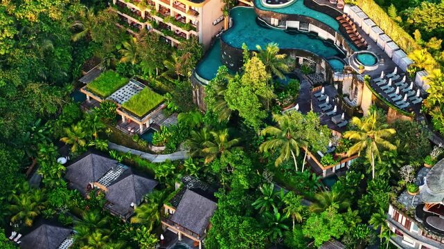 Aerial view of a luxury resort with infinity pools and lush tropical vegetation nestled in the jungle of Bali, Indonesia.