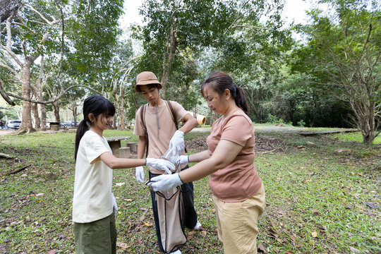 Asian Family Collecting Plastic Waste into Reusable Cloth Bag in Nature