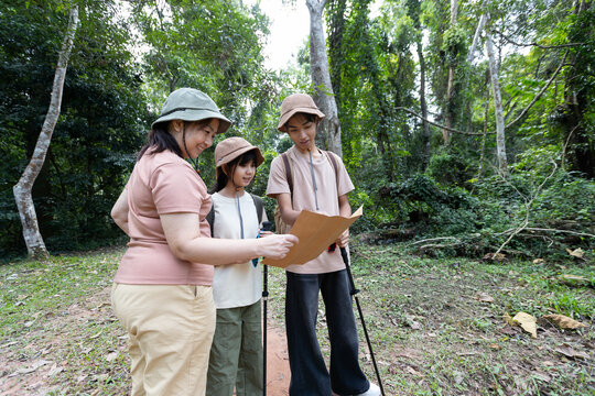 Asian Family Hiking Together and Reading Map on Forest Trail