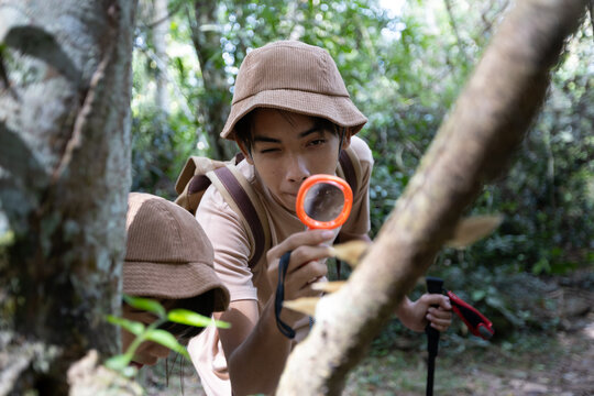 Teenage Boy Using Magnifying Glass to Observe Mushroom in Forest