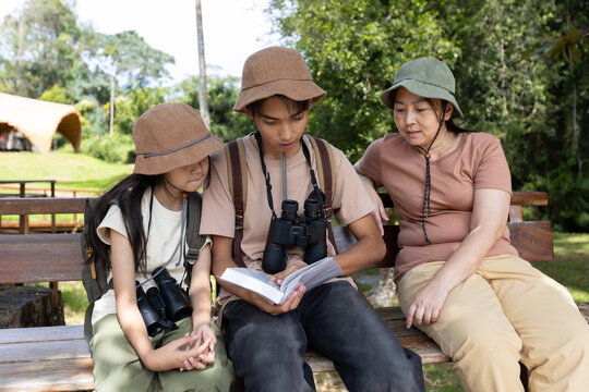 Family Learning About Birds Together Using Bird Guide Outdoors