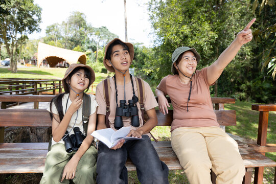 Family Bird Watching Together with Mother Pointing at Birds in Nature Park
