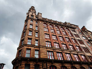 Obraz premium Historic red brick office building with ornate Victorian architecture in Manchester UK under dramatic cloudy sky
