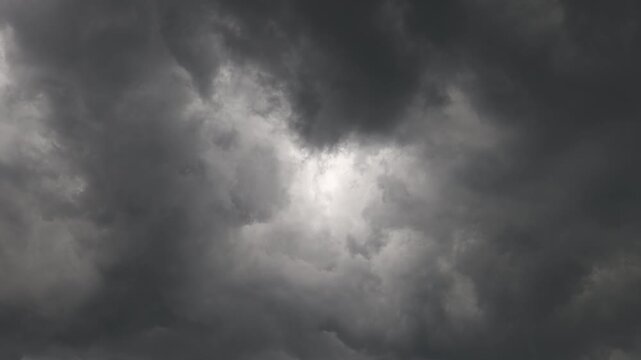 Dramatic storm clouds forming central light pocket during heavy rainstorm
