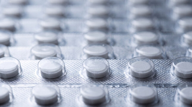 Macro view of white pharmaceutical tablets packaged in silver blister foil