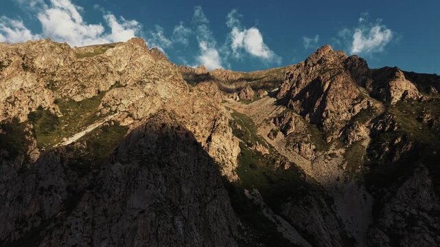 Rugged mountain slope illuminated by sunlight against a blue sky in Ala Archa National Park, Kyrgyzstan