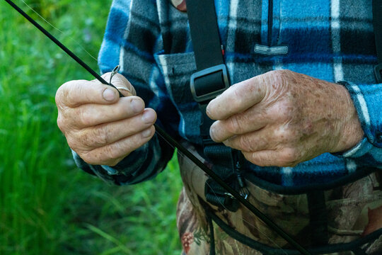 Close-up of the hands of an old fisherman preparing fishing gear.
