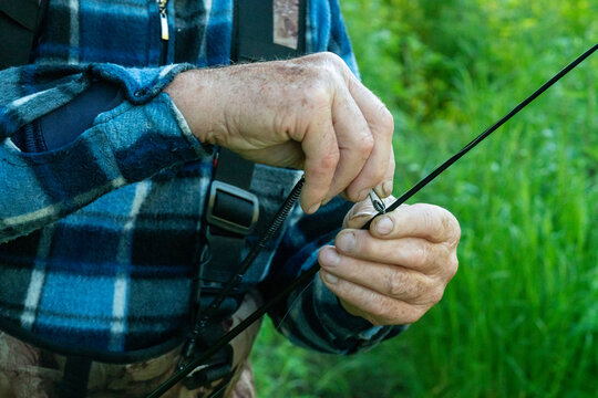 Close-up of the hands of an old fisherman preparing fishing gear.