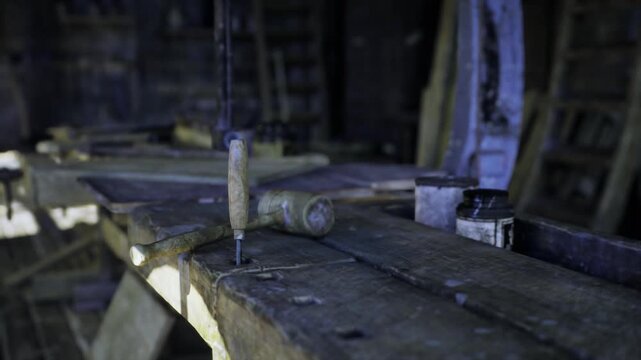 Dusty wooden workbench in dim workshop, closeup of metal vise and worn chisel on aged plank, scattered sawdust and rusted nails, lowkey lighting casting deep