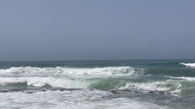 Rolling Ocean Waves Breaking in Layers with White Foam