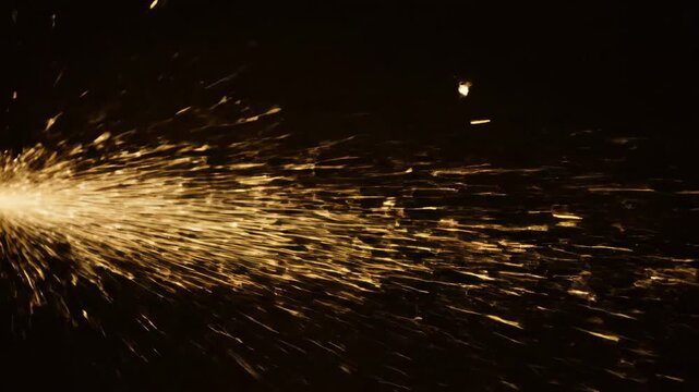 Fiery shower of golden sparks flying horizontally across a deep black background, simulating grinding, welding, or an abstract explosion overlay effect.