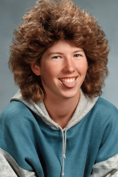 people of ai, yearbook photography of a person with big curly brown mullet, tongue-out grin, wearing teal hoodie, 1980s portrait cyan, photorealistic