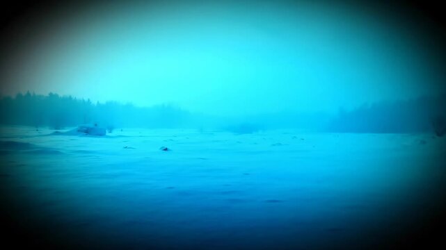 Eerie blue winter landscape with heavy mist covering a snow field under the dark atmospheric night sky, featuring a mysterious forest line in the background.