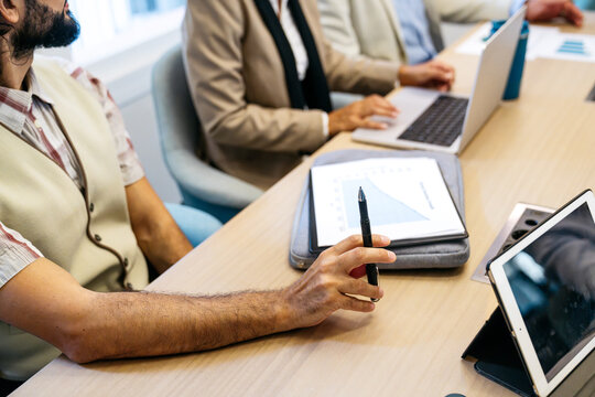 Diverse team of professionals brainstorming ideas and analyzing graphs during a business meeting in contemporary coworking space