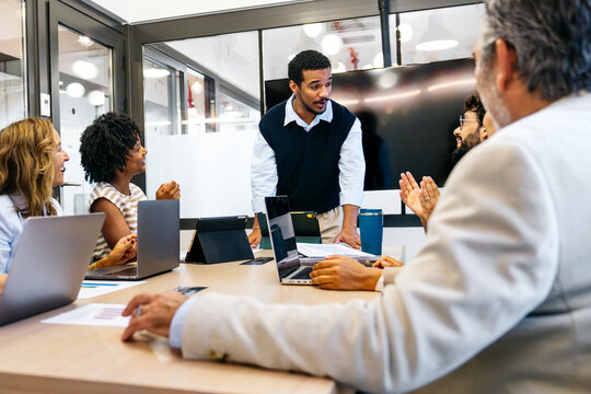 Group of multi ethnic professionals actively participating in an informal brainstorming session inside a modern coworking office space
