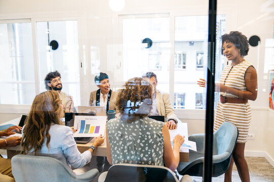 Group of diverse business professionals discussing project metrics during a meeting in a contemporary coworking office space