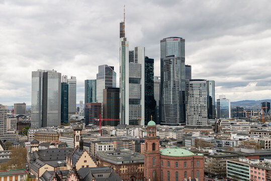 FRANKFURT AM MAIN, GERMANY &mdash; APRIL 4, 2026: Aerial view of the modern skyscrapers in the financial district rising above St. Paul's Church under a cloudy sky