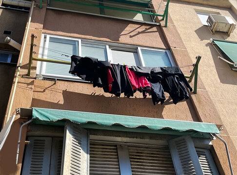 Ropa colada colgada en tendedero secar al aire orear exterior terraza de casa fachada con cuerdas y pinzas ropa tendida secando humedad y malos olores 
