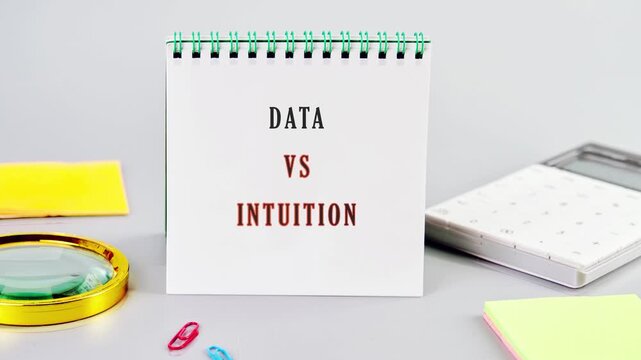 Two signs display the words data and intuition in a simple setting with stationery. This highlights the concept of decision making and analysis