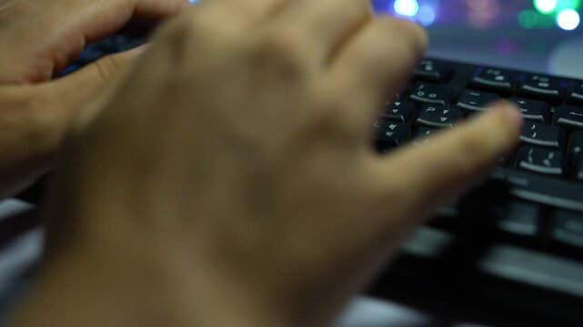 Close-up of hands typing on a computer keyboard with colorful blurred lights in the background