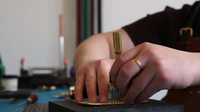Close-up of Punching Holes in Leather 4k video. Artisan hands using a heavy mallet and a brass stitching punch to make holes in leather