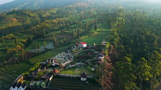 Aerial view of Rest Area Tegal Ombo surrounded by lush terraced fields and green hills in Kecamatan Candiroto, Jawa Tengah, Indonesia.