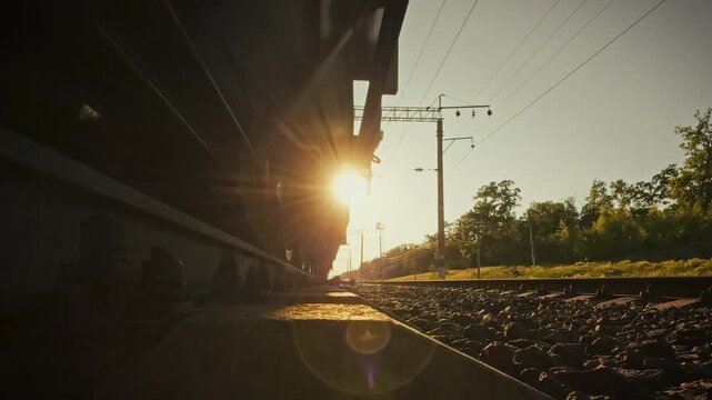 On sunlit railway track, the wheelsets of a freight train flash over the rails, showcasing rail transport. This close-up highlights efficient freight delivery and modern transportation infrastructure
