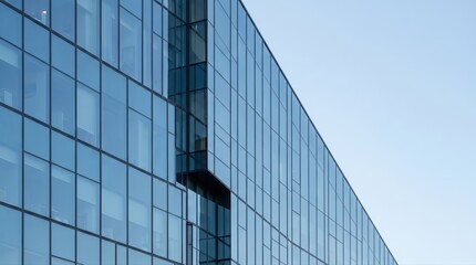 Obraz premium Modern office building glass facade reflecting clear blue sky in urban architectural design concept.