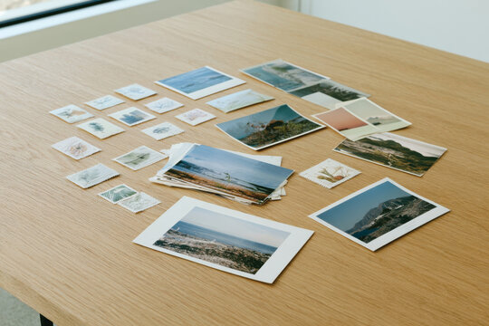 A curated collection of various photographs and nature-themed stamps artfully arranged on a simple wooden table, inviting reflection and appreciation for nature's beauty.