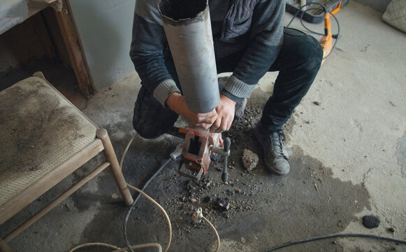 Caucasian worker using concrete core drilling machine.