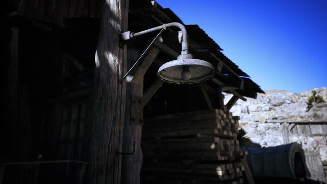 Metal showerhead with single droplet catching light closeup texture study of corroded metal, rope shadow, aged timber backdrop, intense blue sky and arid
