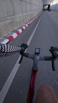 POV footage of a road cyclist riding toward an urban underpass tunnel, capturing city transportation, cycling, infrastructure, outdoor fitness and first person travel.