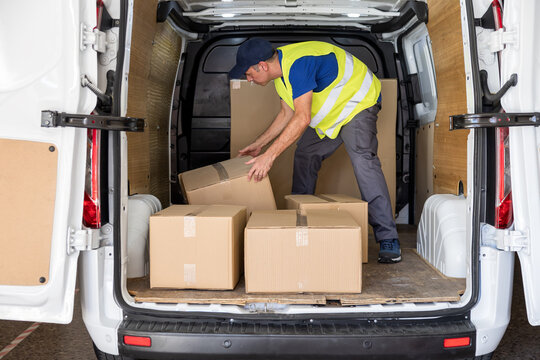 Man worker organizing parcels by delivery order inside cargo van