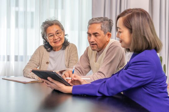 thoughtful asian senior couple reviewing health insurance coverage from a female professional agent on digital tablet in living room at home