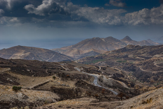 Panoramic view of a rugged arid mountainous landscape under dramatic dark storm clouds in desert