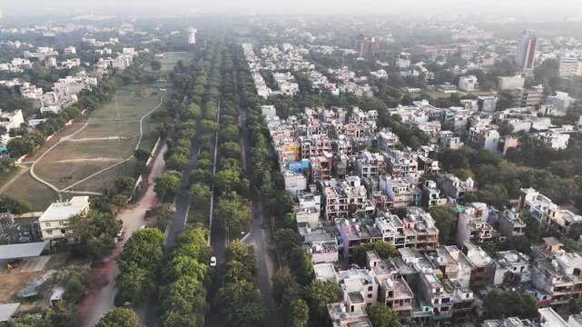 Aerial view of a dense residential neighborhood with tree-lined streets and green spaces in Greater Noida, Uttar Pradesh, India.