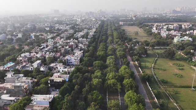 Aerial view of dense residential neighborhood with tree-lined streets and adjacent parkland in Greater Noida, Uttar Pradesh, India.