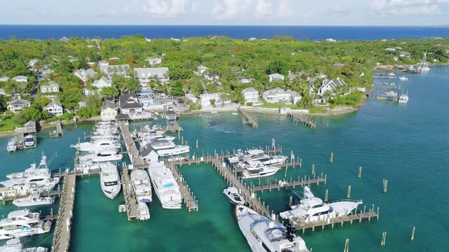 Aerial view of luxury yachts docked at the marina in Harbour Island, surrounded by turquoise waters and lush tropical vegetation in Dunmore Town, Harbour Island, The Bahamas.