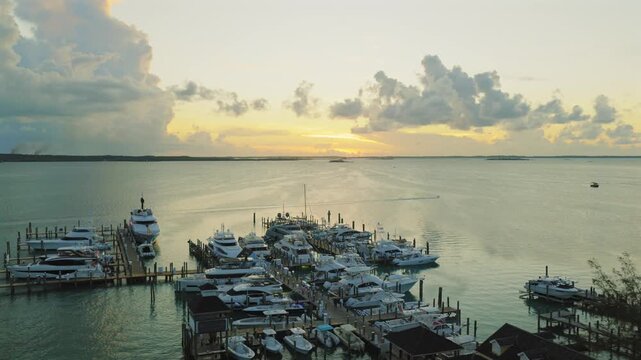 Aerial view of a marina filled with luxury yachts during a golden sunset in Dunmore Town, Harbour Island, The Bahamas.