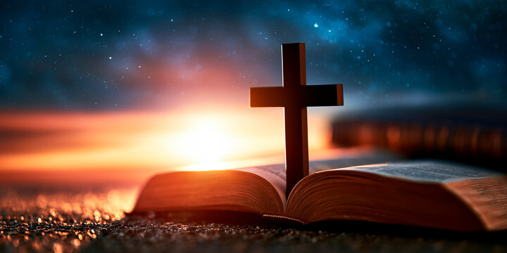 Christian cross and holy bible illuminated by dawn light on a cosmic background