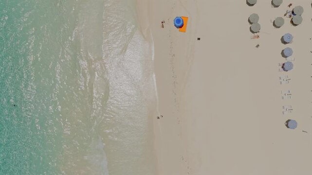 Aerial view of Pink Beach with turquoise water, white sand, and rows of beach umbrellas in Rock Sound, South Eleuthera, The Bahamas.